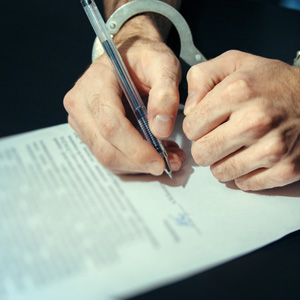 a man wearing hand cuffs signing a document